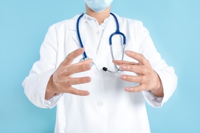 Doctor holding something on light blue background, closeup