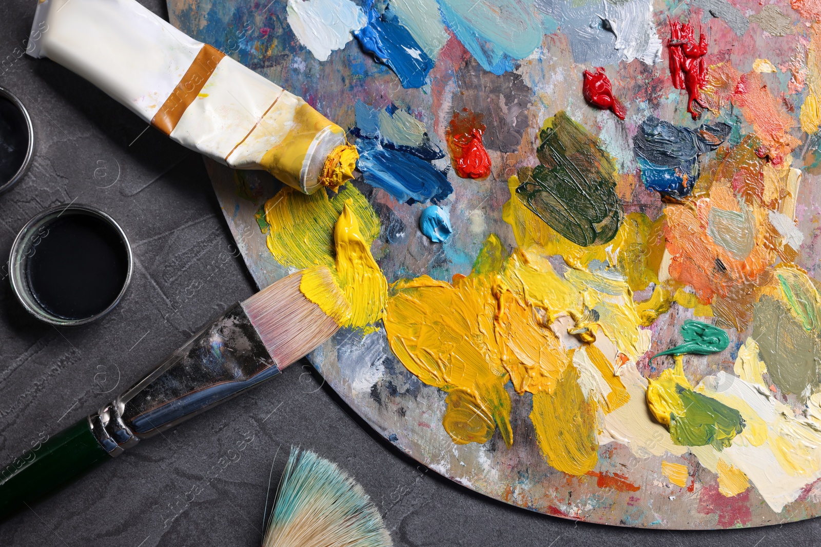 Photo of Artist's palette, brushes and paints on grey table, flat lay