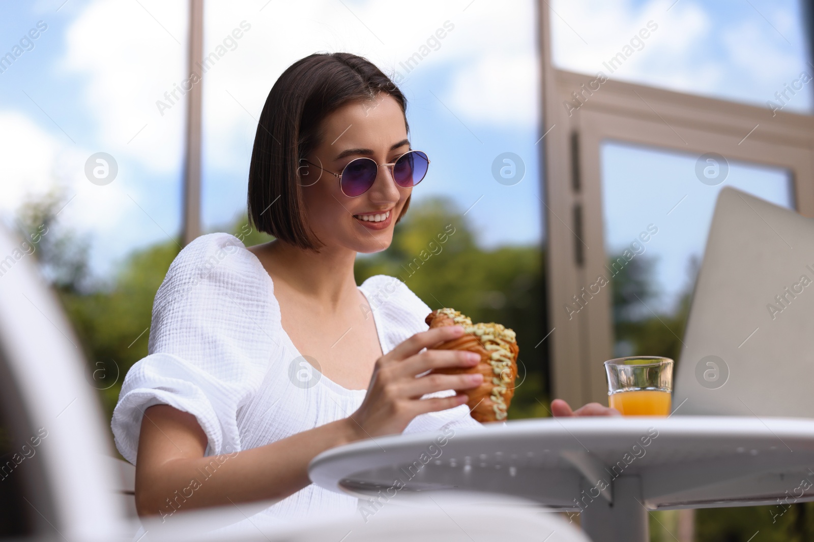 Photo of Happy woman having tasty breakfast in outdoor cafe