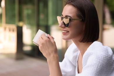 Happy woman having breakfast in outdoor cafe, space for text