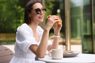 Photo of Happy woman having tasty breakfast in outdoor cafe