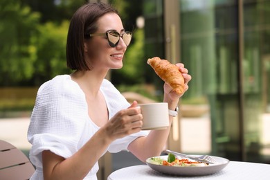 Photo of Happy woman having tasty breakfast in outdoor cafe