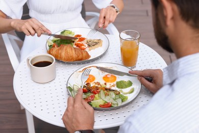 Photo of Couple having tasty breakfast in outdoor cafe, closeup
