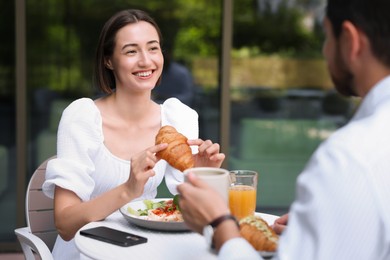 Photo of Happy couple having breakfast in outdoor cafe