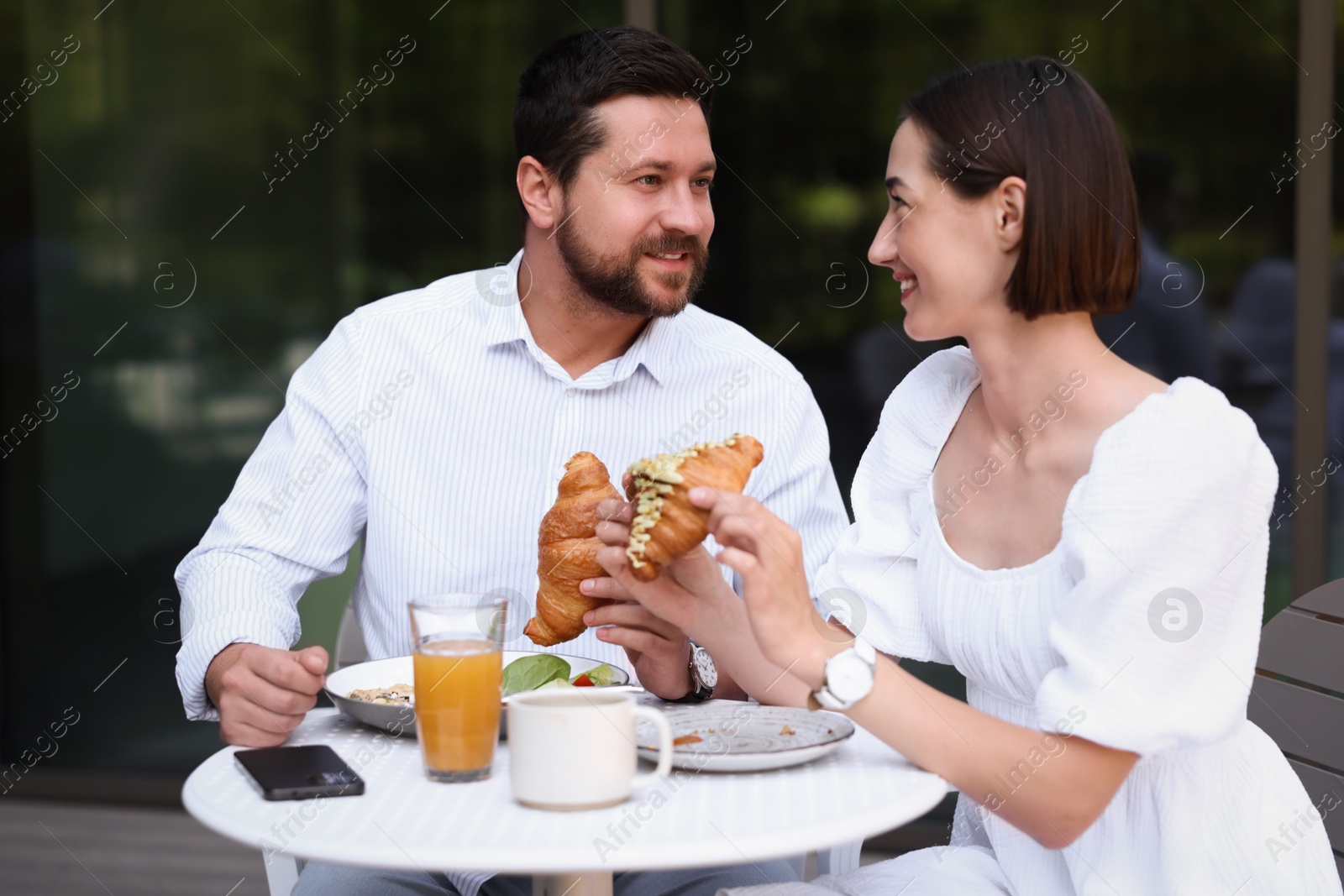 Photo of Happy couple having breakfast in outdoor cafe