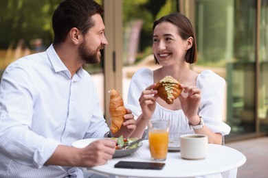 Photo of Happy couple having breakfast in outdoor cafe