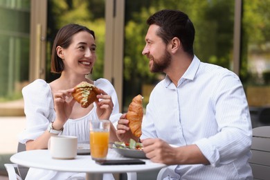 Photo of Happy couple having breakfast in outdoor cafe