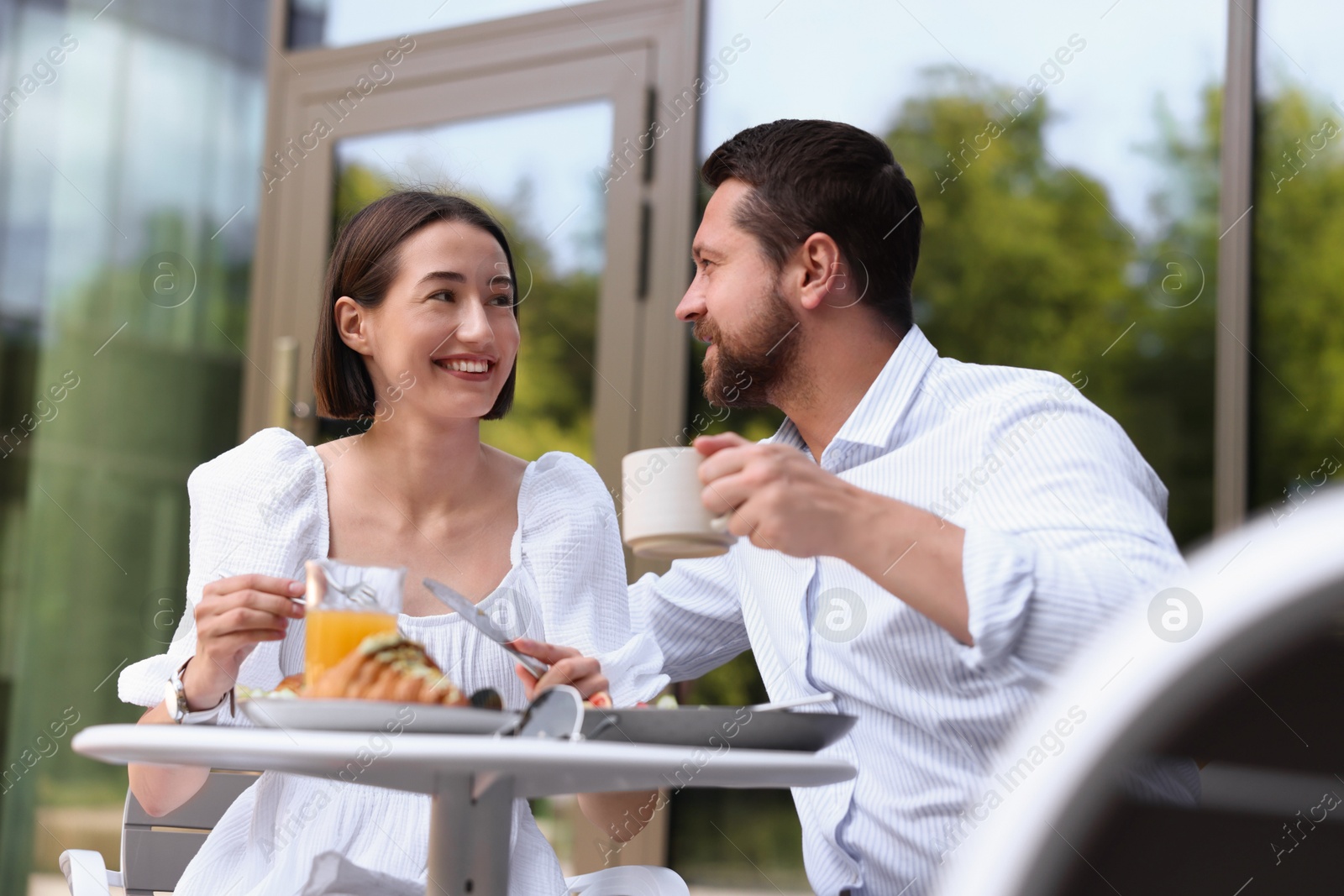 Photo of Happy couple having breakfast in outdoor cafe