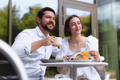 Photo of Happy couple having breakfast in outdoor cafe