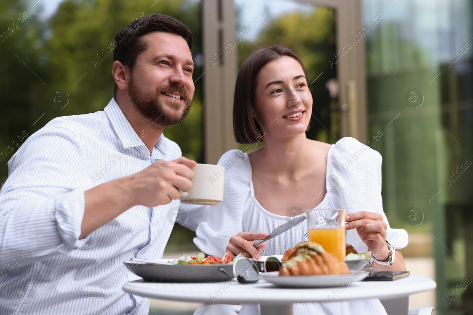 Photo of Happy couple having breakfast in outdoor cafe