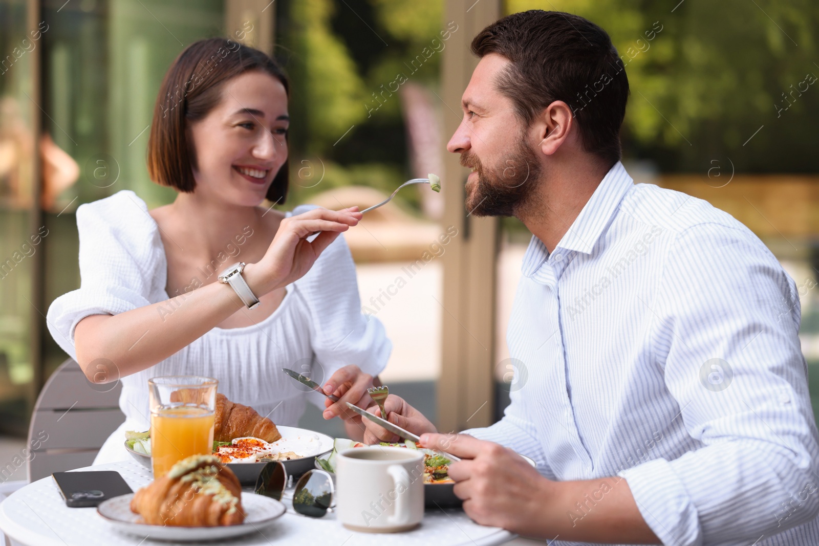 Photo of Happy couple having breakfast in outdoor cafe