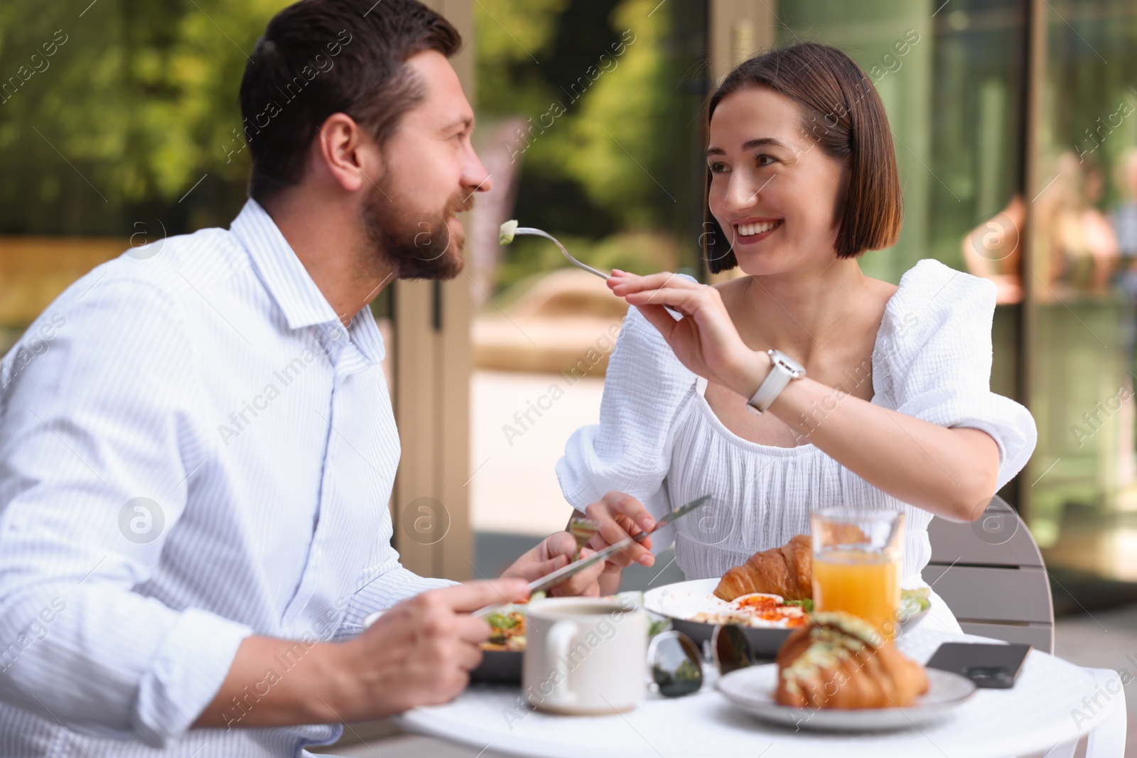 Photo of Happy couple having breakfast in outdoor cafe