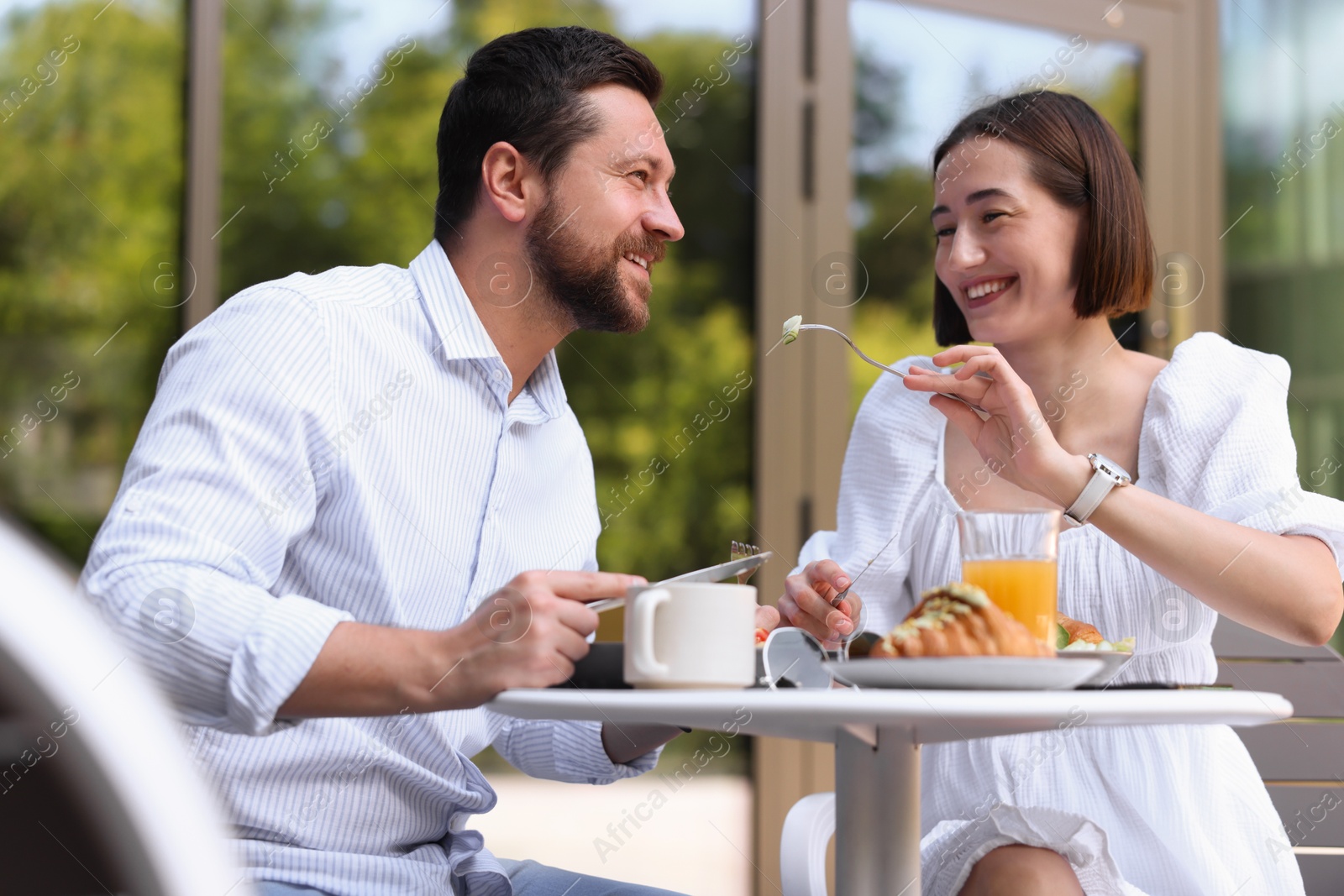 Photo of Happy couple having breakfast in outdoor cafe