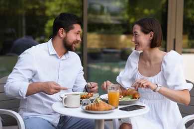 Photo of Happy couple having breakfast in outdoor cafe