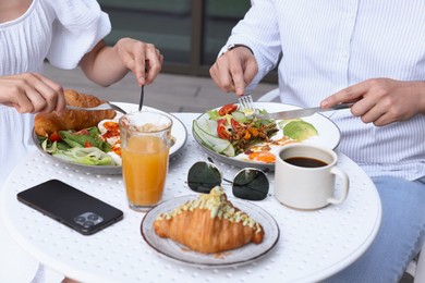 Couple having tasty breakfast in outdoor cafe, closeup