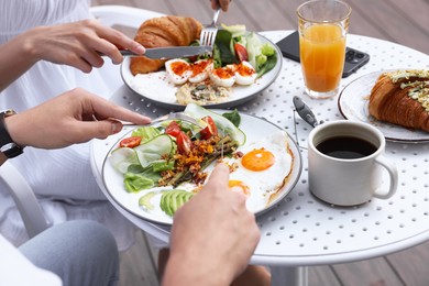 Photo of Couple having tasty breakfast in outdoor cafe, closeup