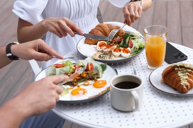 Couple having tasty breakfast in outdoor cafe, closeup