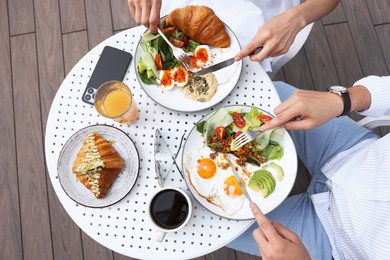 Couple having tasty breakfast in outdoor cafe, top view