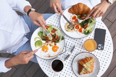 Couple having tasty breakfast in outdoor cafe, top view