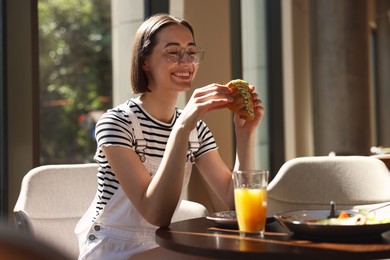 Photo of Happy woman having tasty breakfast in cafe