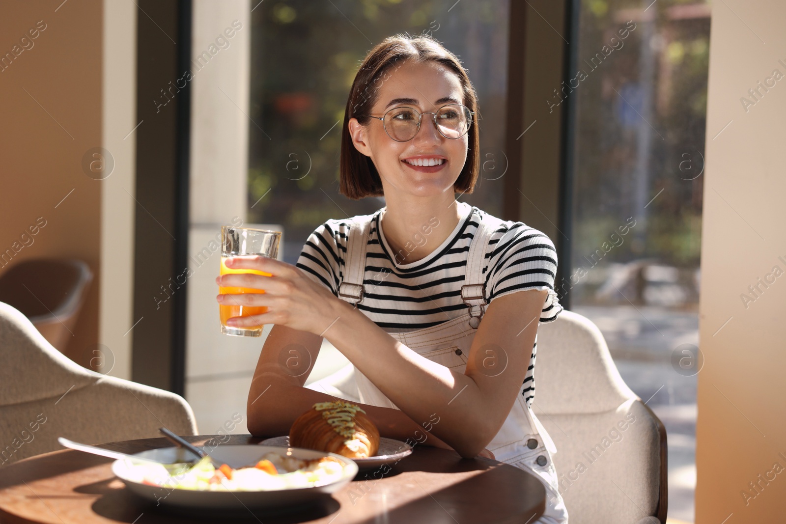 Photo of Happy woman having tasty breakfast in cafe