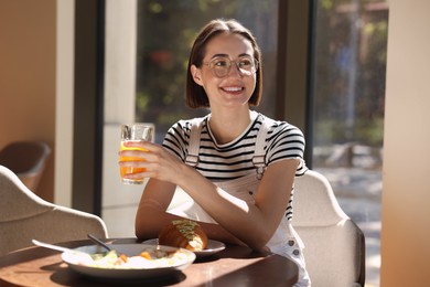 Photo of Happy woman having tasty breakfast in cafe