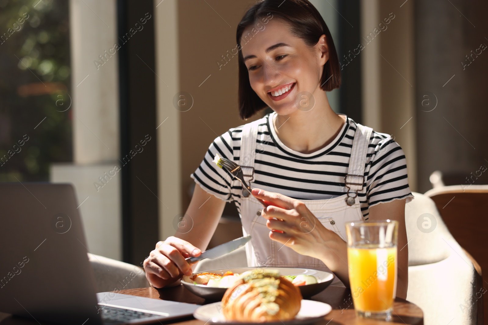 Photo of Happy woman having tasty breakfast in cafe