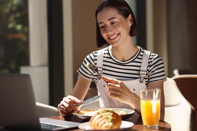 Happy woman having tasty breakfast in cafe