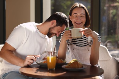 Photo of Happy couple having tasty breakfast in cafe