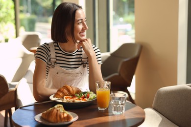 Happy woman having tasty breakfast in cafe