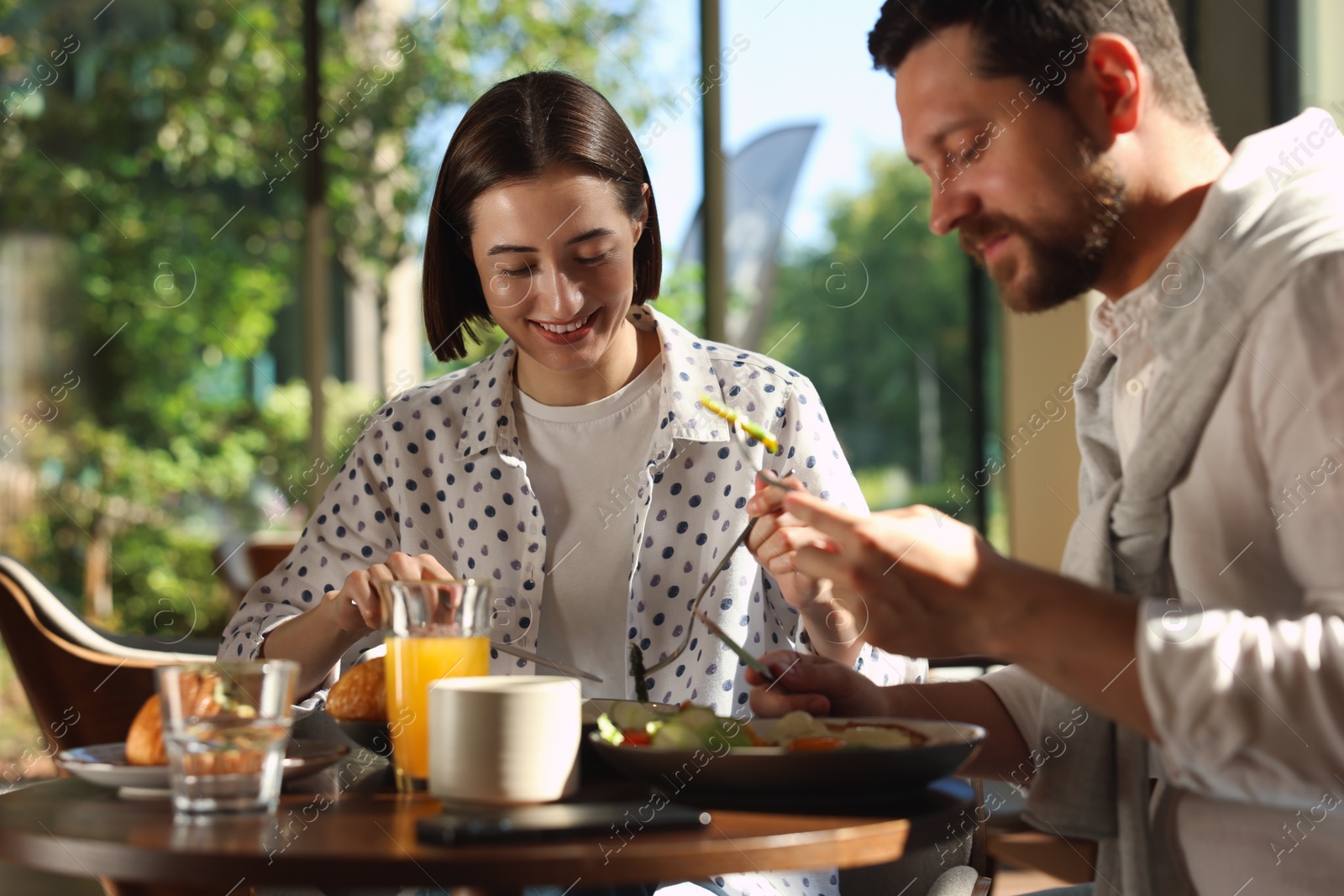 Photo of Happy couple having tasty breakfast in cafe