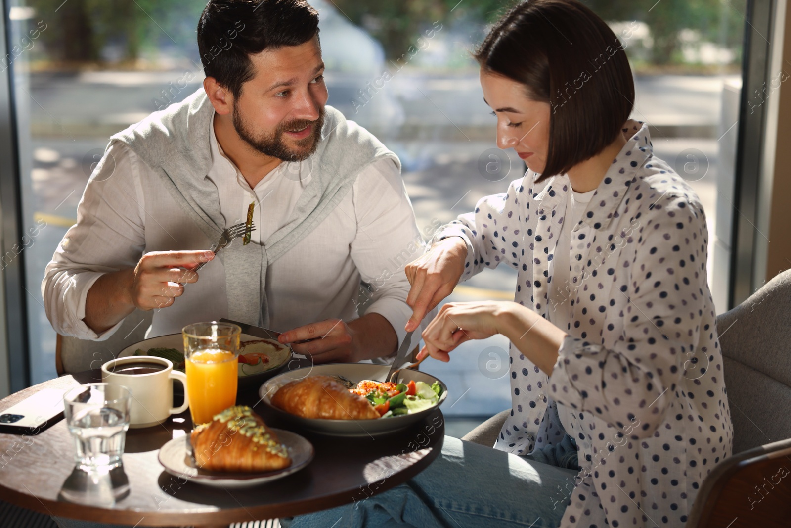 Photo of Happy couple having tasty breakfast in cafe