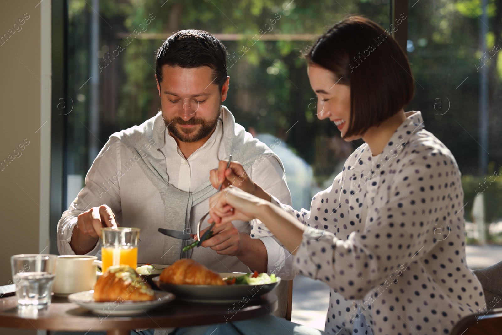 Photo of Happy couple having tasty breakfast in cafe