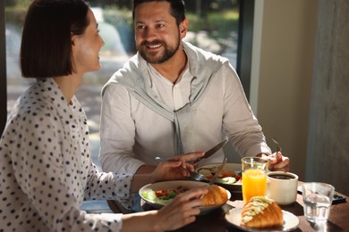 Happy couple having tasty breakfast in cafe