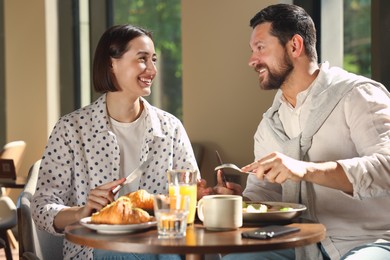 Photo of Happy couple having tasty breakfast in cafe