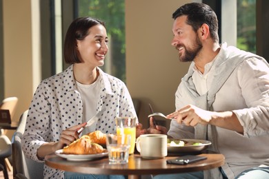 Happy couple having tasty breakfast in cafe