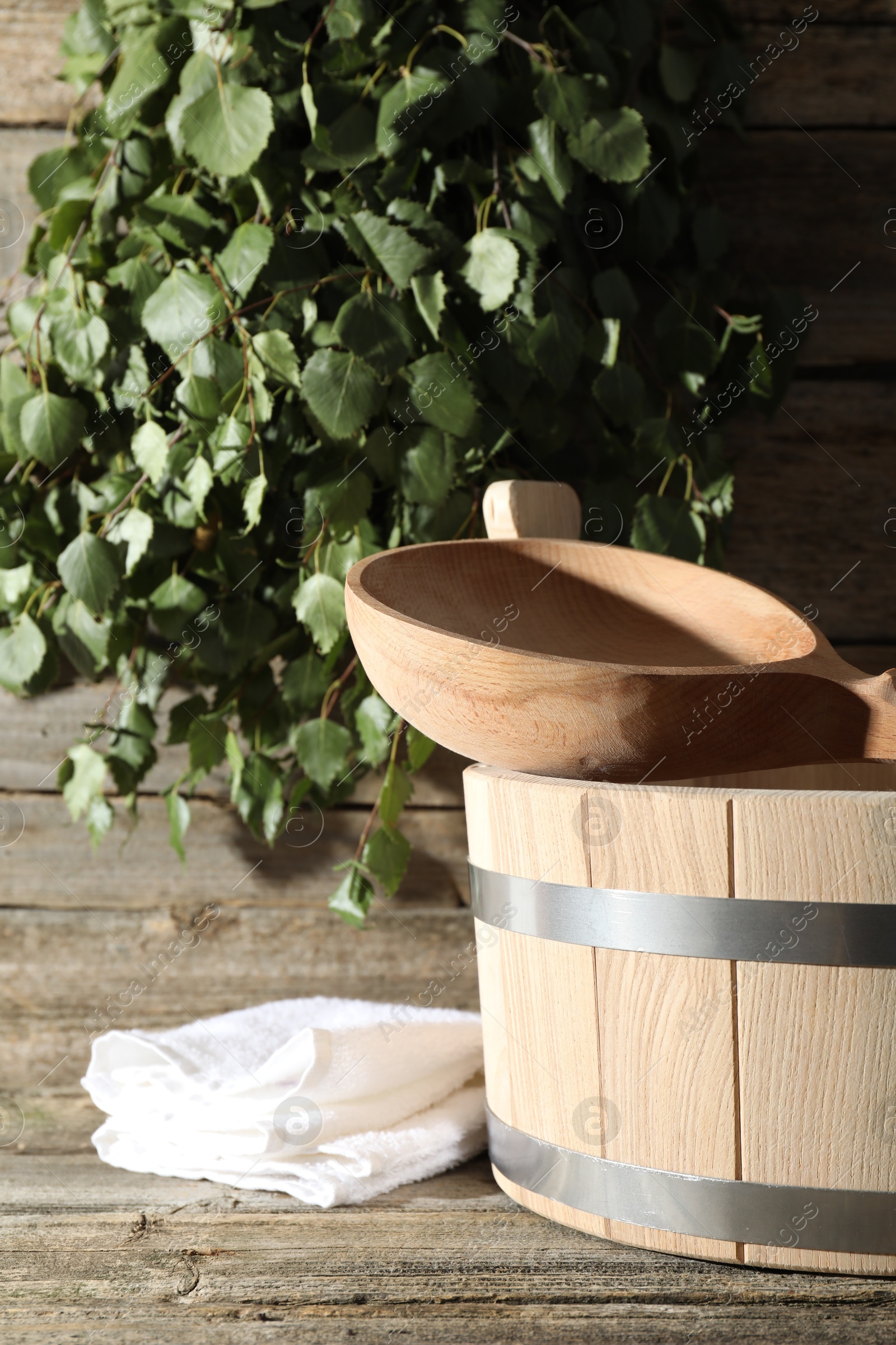 Photo of Sauna equipment. Bucket, ladle and towel on wooden surface