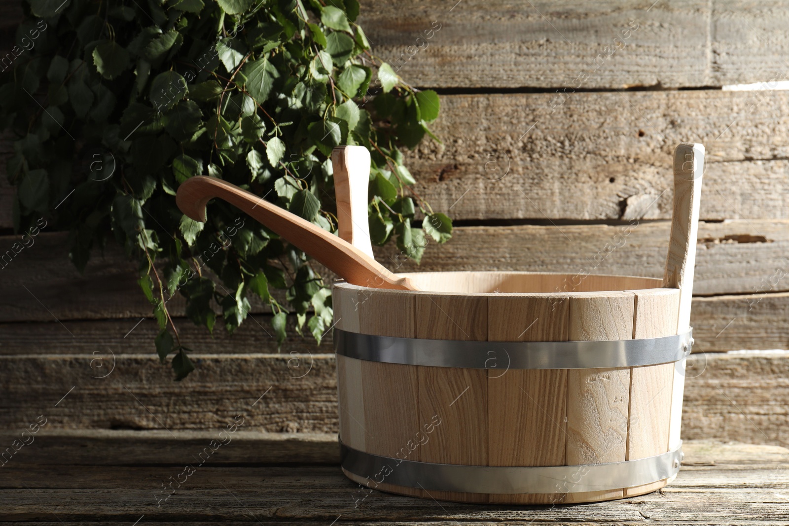 Photo of Sauna equipment. Bucket and ladle on wooden surface