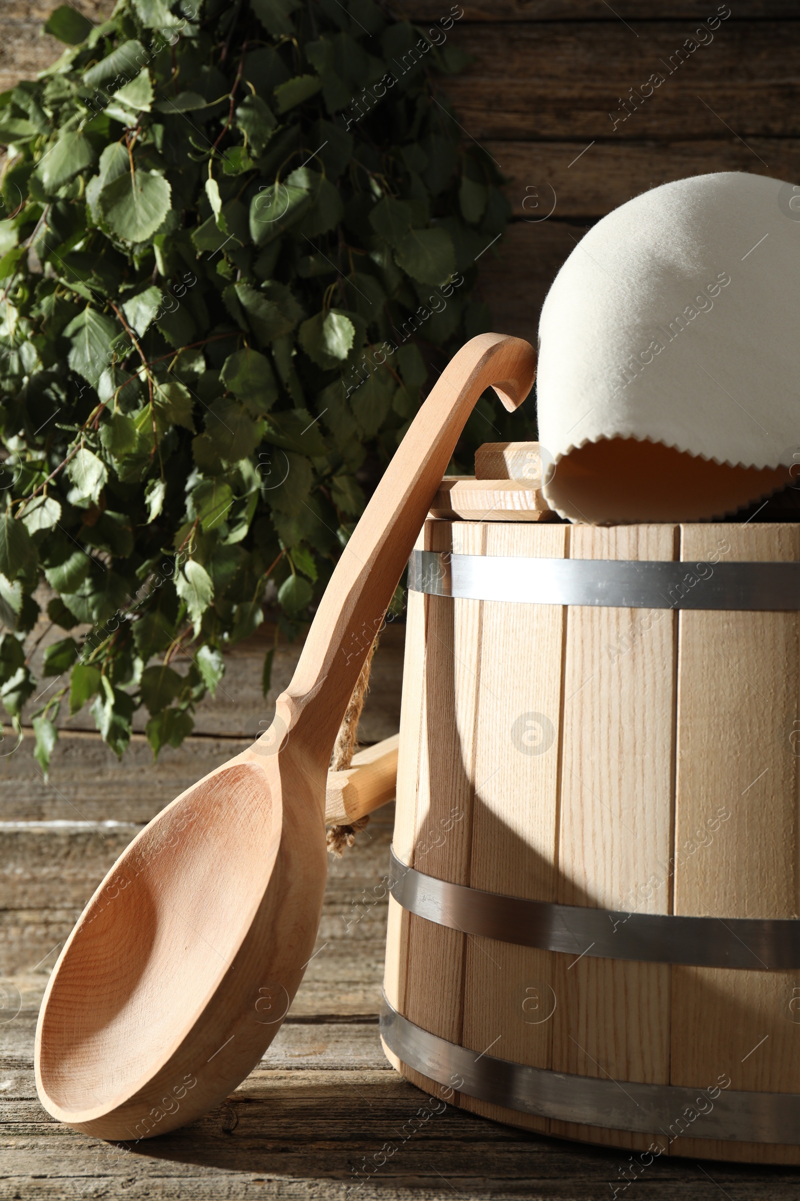 Photo of Sauna equipment. Bucket, felt wool hat and ladle on wooden surface