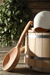 Photo of Sauna equipment. Bucket, felt wool hat and ladle on wooden surface