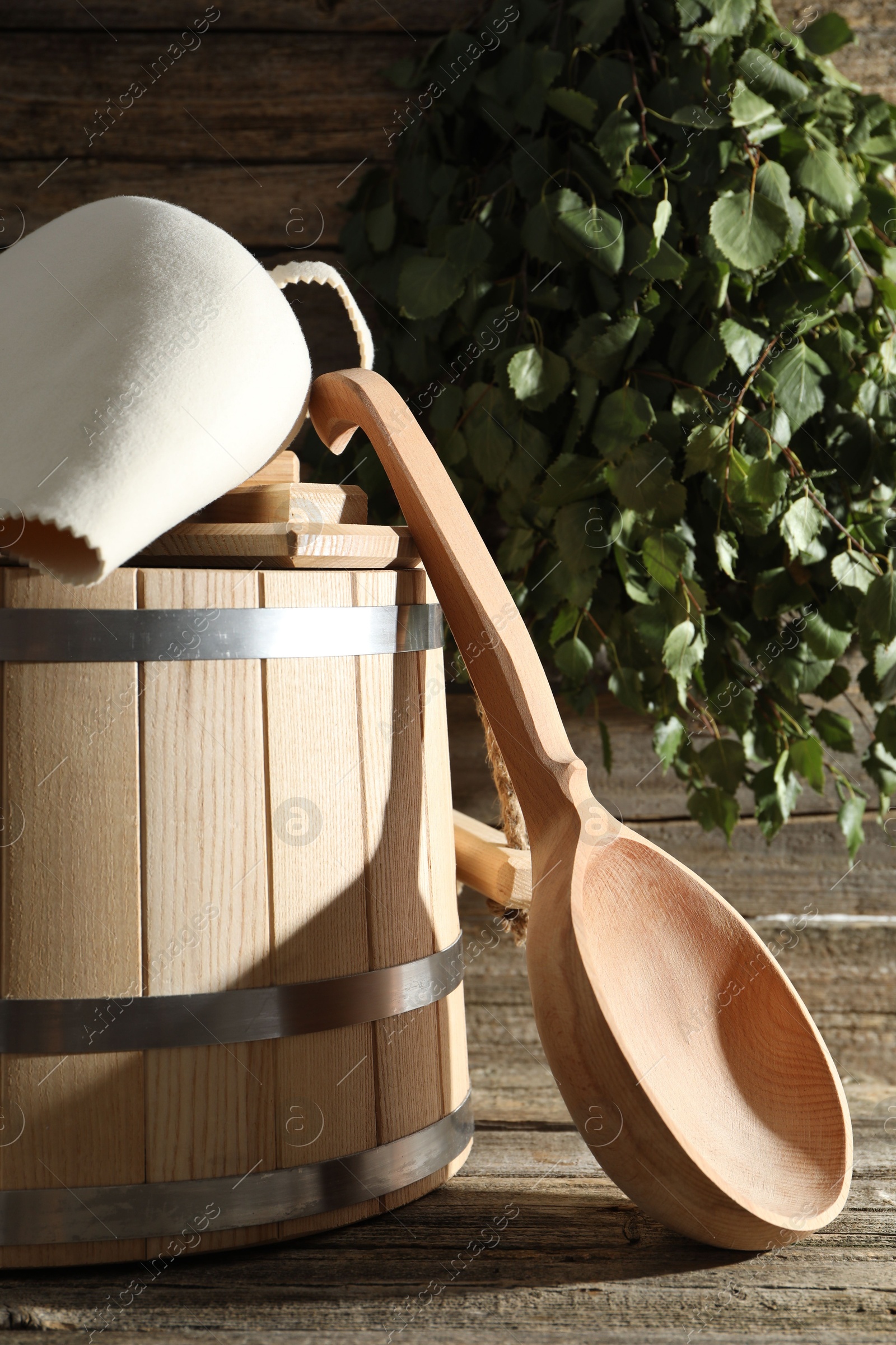 Photo of Sauna equipment. Bucket, felt wool hat and ladle on wooden surface