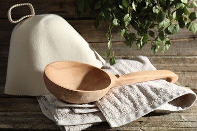 Photo of Sauna equipment. Felt wool hat, ladle and towel on wooden surface