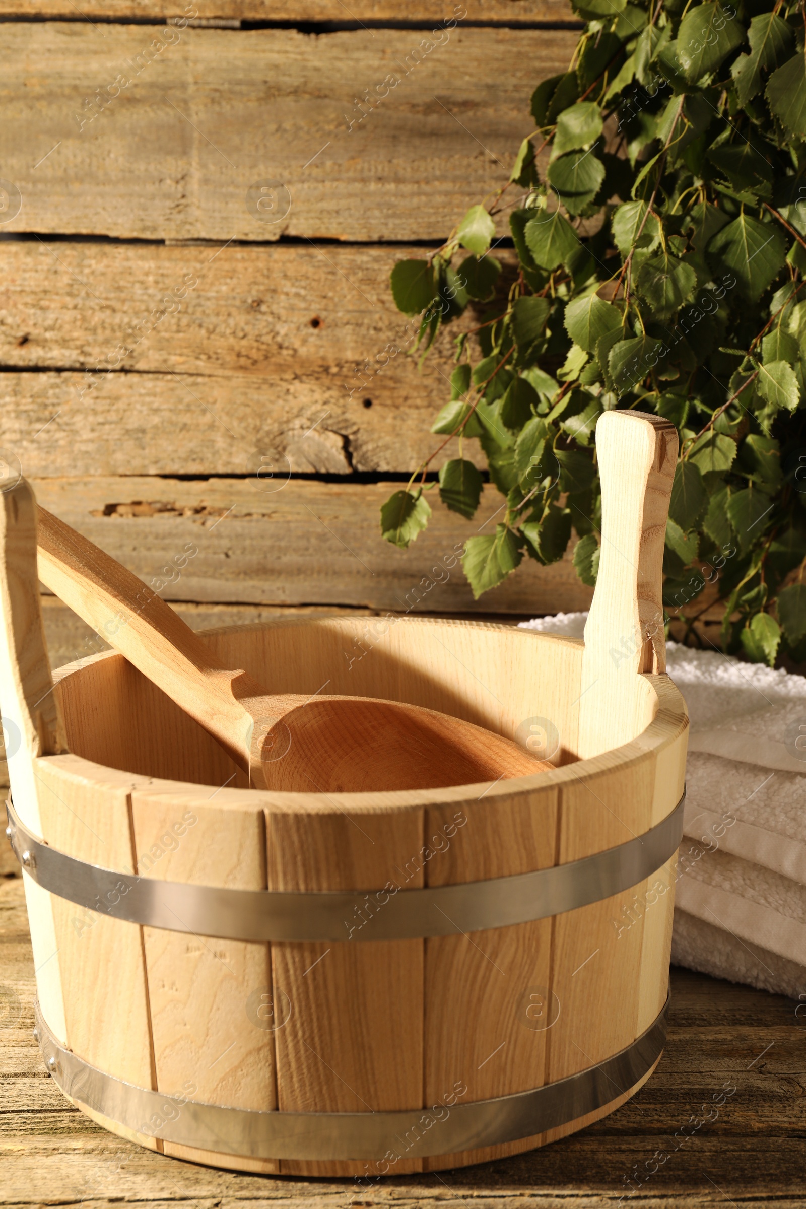 Photo of Sauna equipment. Bucket with ladle and towel on wooden surface