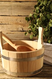 Sauna equipment. Bucket with ladle and towel on wooden surface