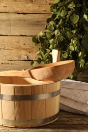 Photo of Sauna equipment. Bucket with ladle and towel on wooden surface