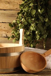 Photo of Sauna equipment. Bucket with ladle and towel on wooden surface