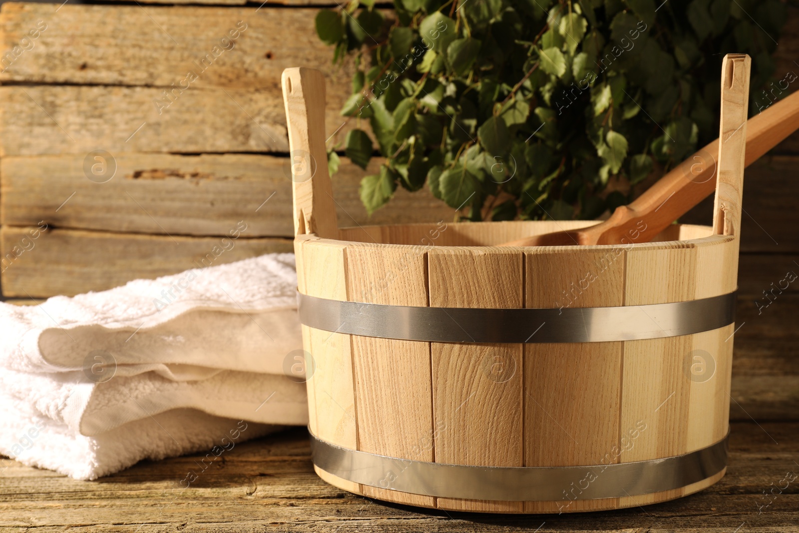 Photo of Sauna equipment. Bucket, ladle and towel on wooden surface