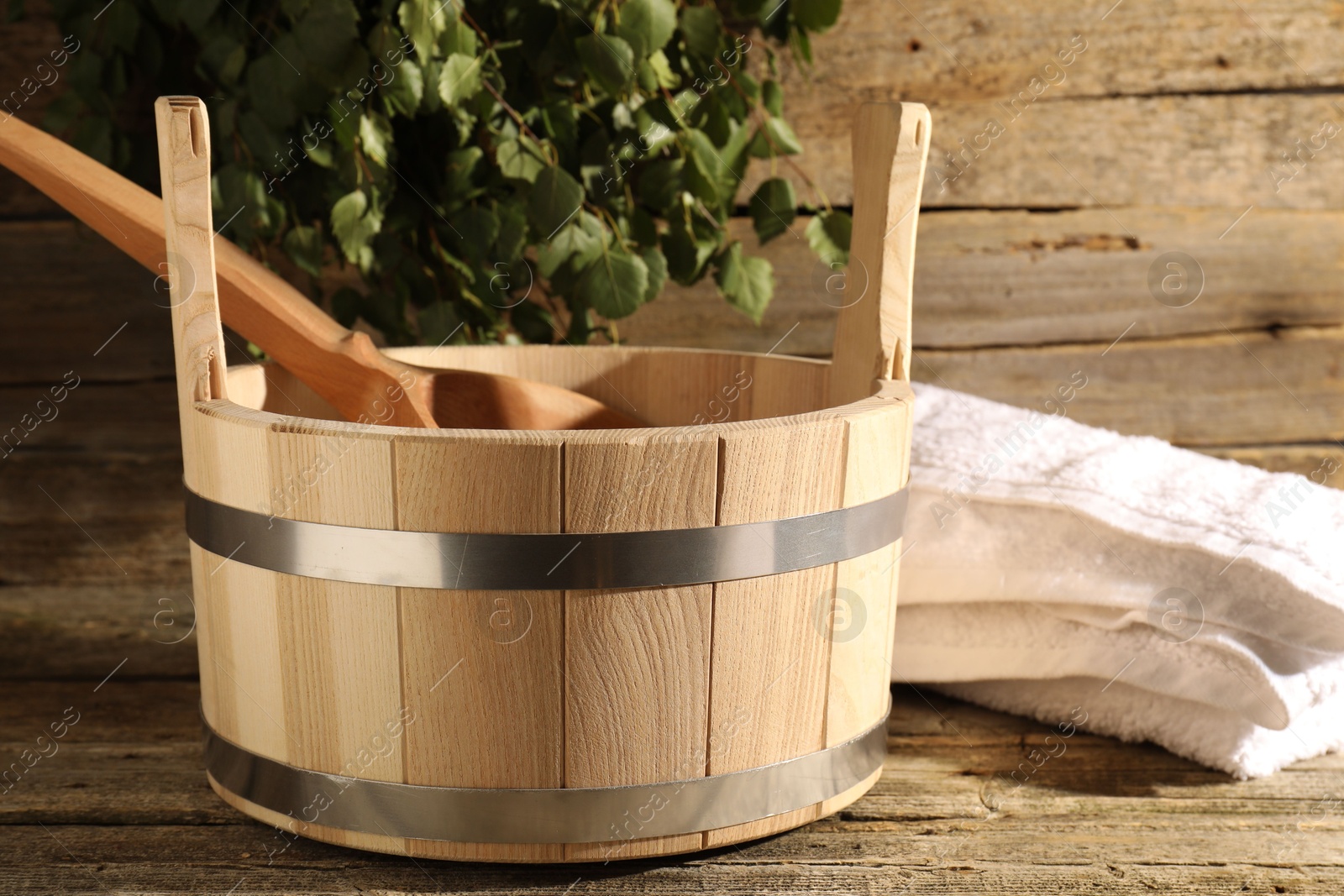 Photo of Sauna equipment. Bucket, ladle and towel on wooden surface