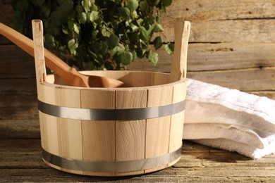 Sauna equipment. Bucket, ladle and towel on wooden surface