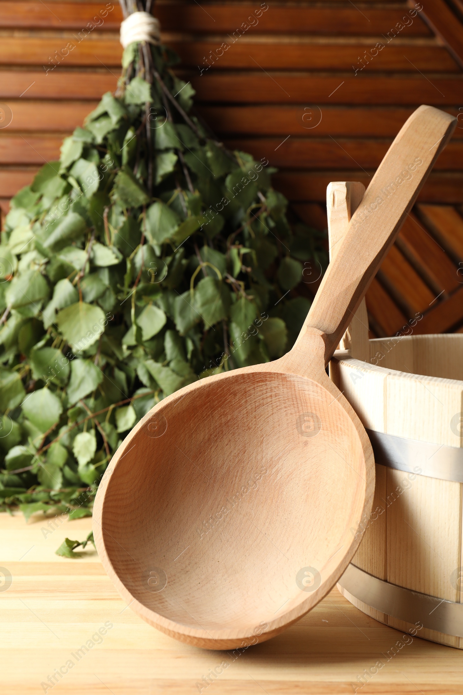 Photo of Sauna equipment. Bucket, ladle and birch whisk on wooden surface, closeup